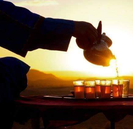 Moroccan mint tea being poured at sunset in the desert